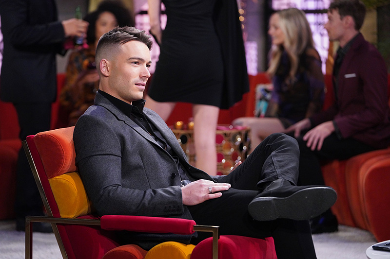 noah newman sits in a red and orange velvet chair at glam club