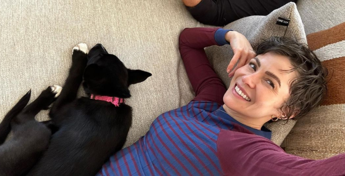 linsey godfrey laying on the couch with her adorable new puppy, evie.