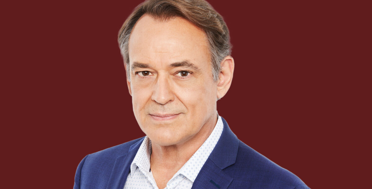 jon lindstrom from general hospital in a blue suit is against a backdrop that is maroon.