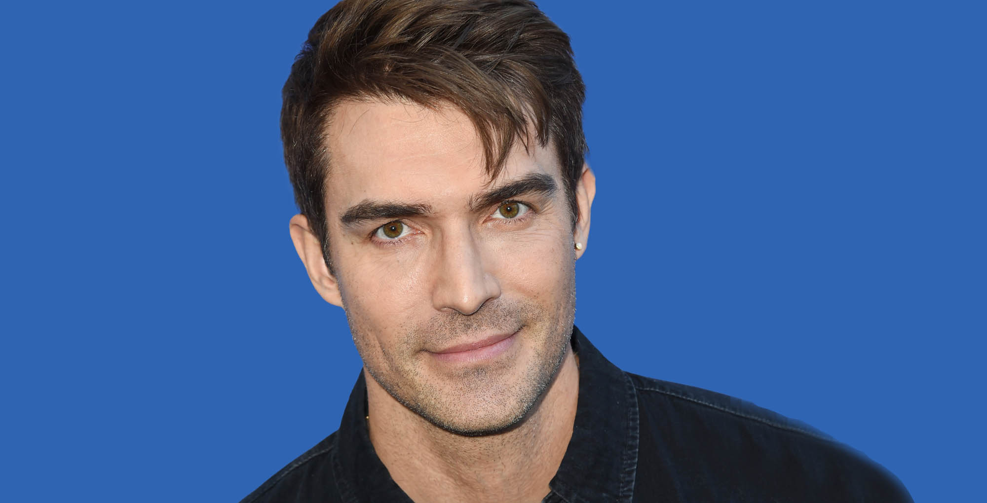 days of our lives star peter porte wearing black against a blue background.