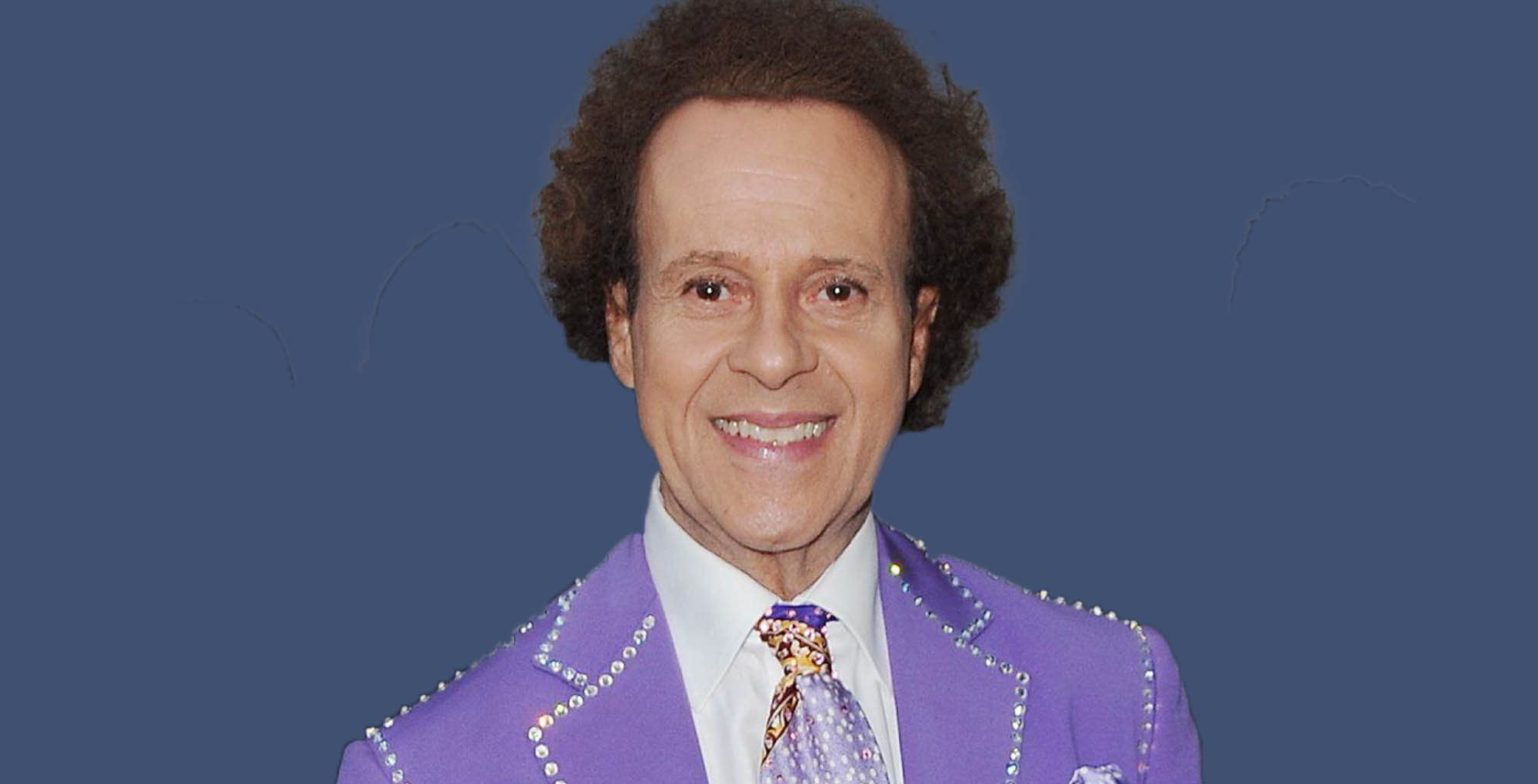 general hospital alum richard simmons wearing purple against a blue background.