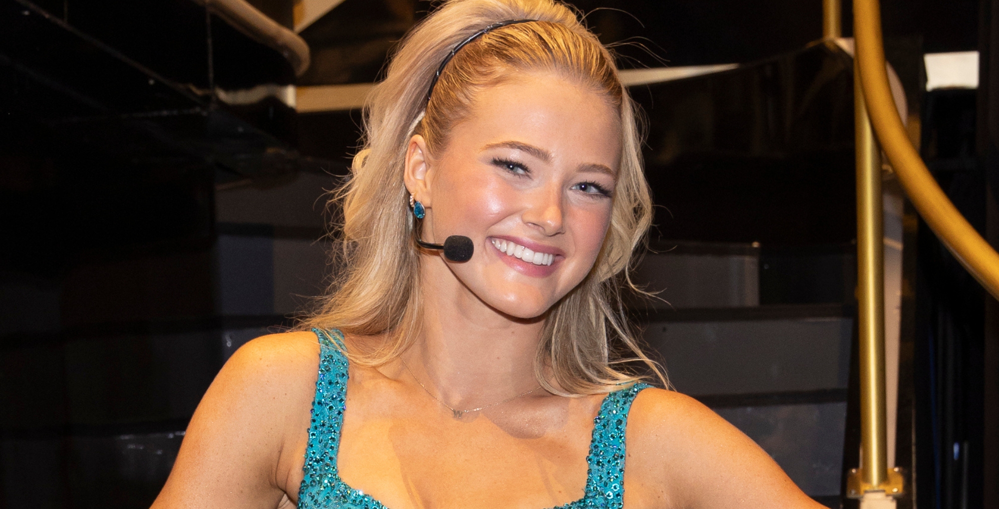 Rylee Arnold on the DWTS stage in a green dress. She's wearing a mic.